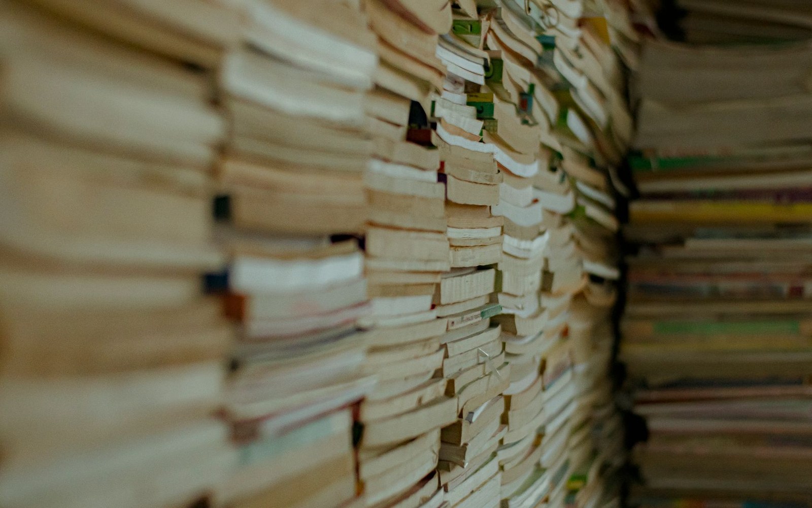 Tall stacks of books with worn page edges viewed at close range