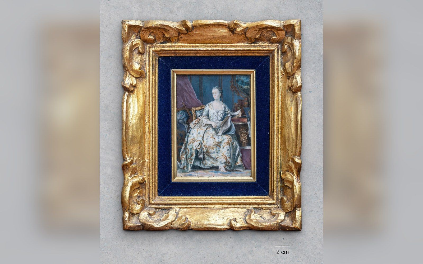 A miniature portrait of a seated woman in an ornate gilded frame with blue velvet matting
