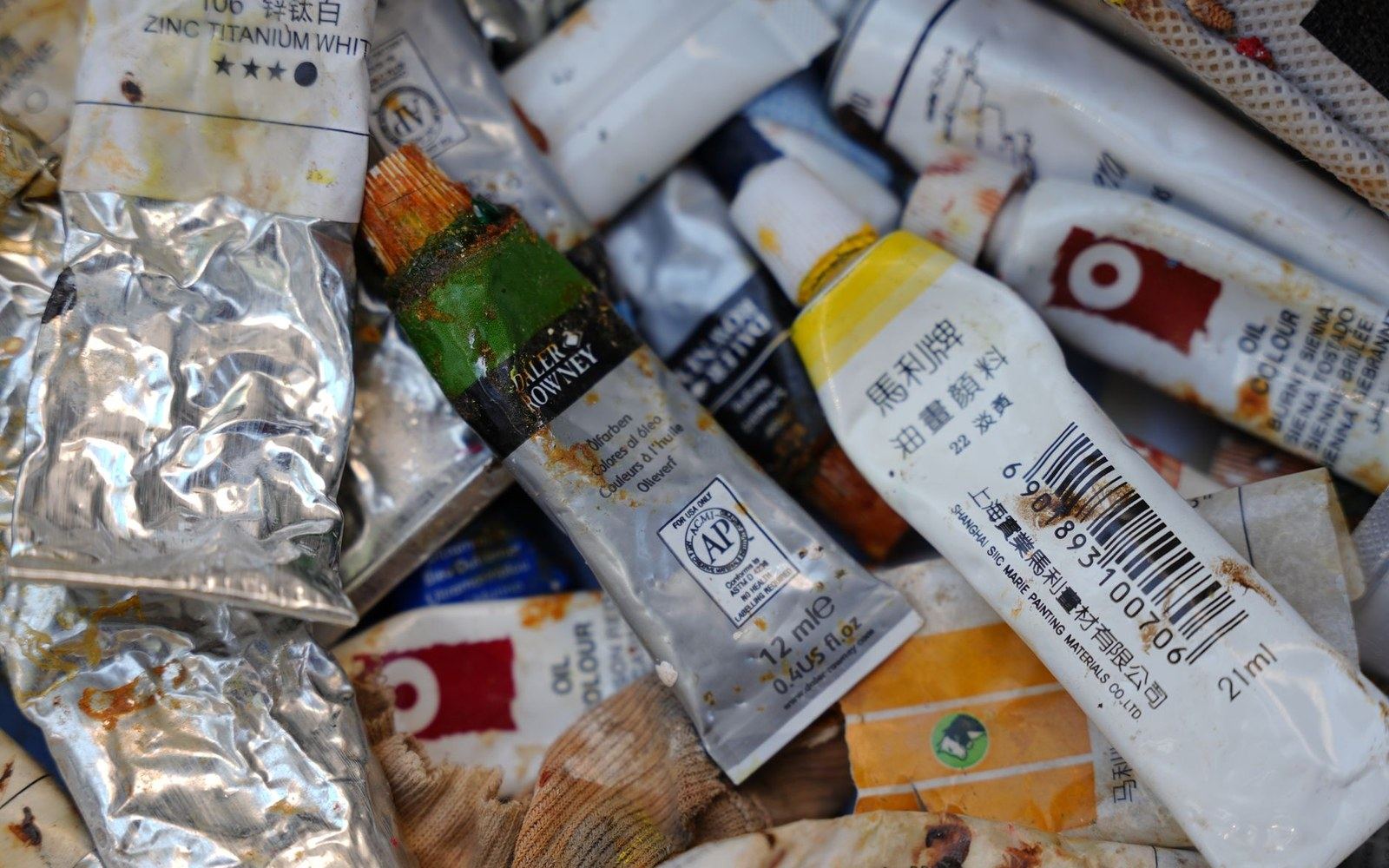 Squeezed and crumpled oil paint tubes with Chinese and English labels piled together